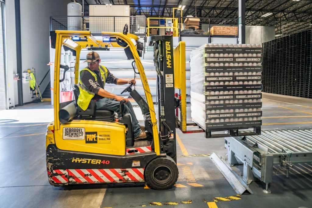 Crafting Captivating Headlines: Your awesome post title goes here A warehouse worker maneuvers a forklift to transport crates for brewing company storage.